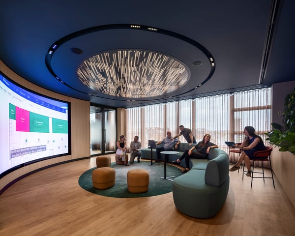 People sitting on couch around large screen collaborating. 